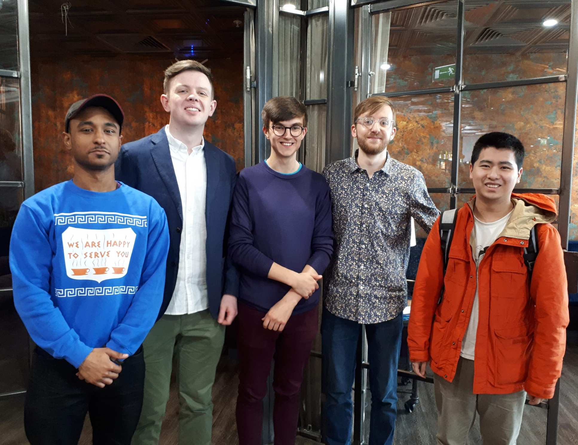 Five men pose for a photo smiling at camera