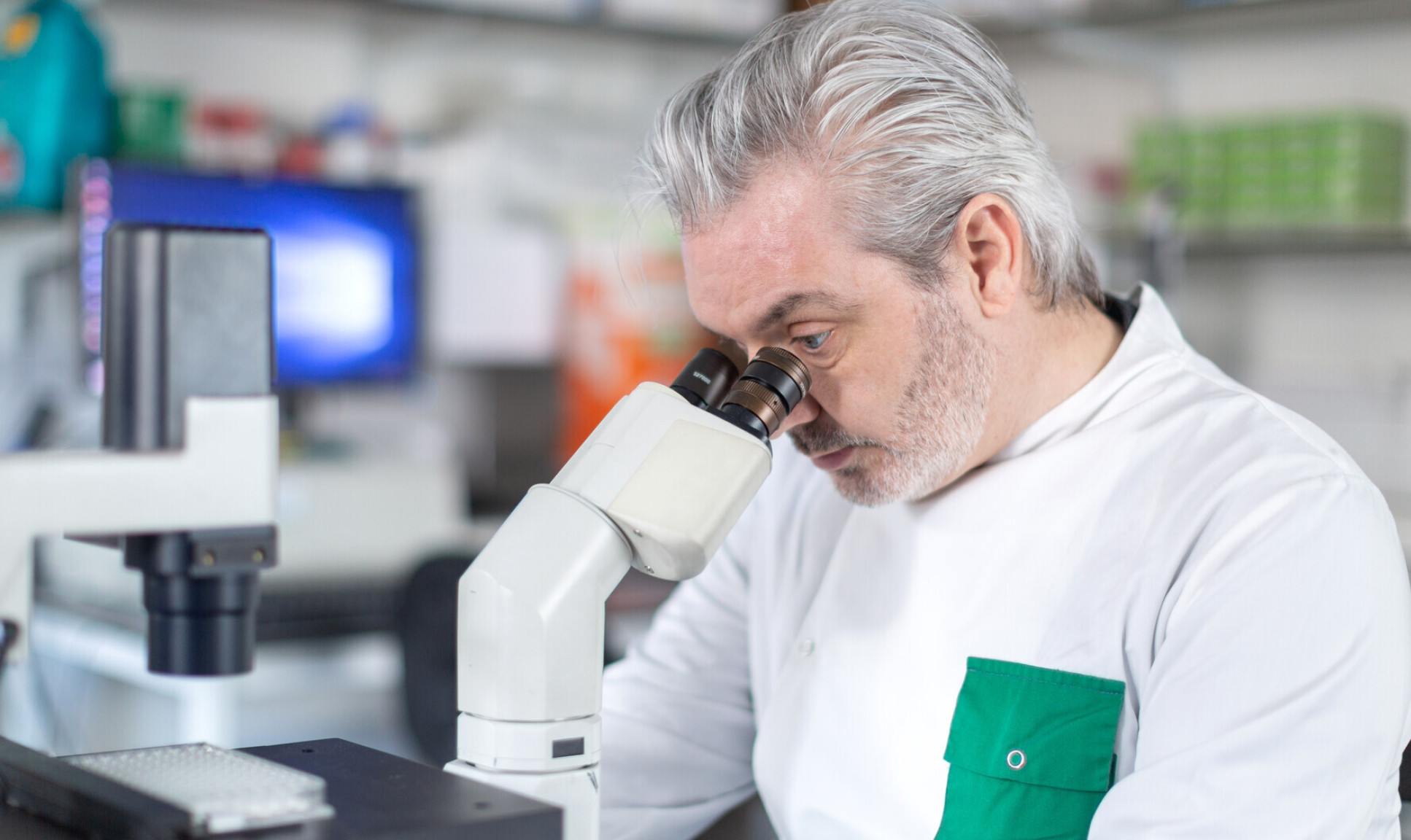 Dr Paul McKay looking through a microscope in Imperial's COVID vaccine research lab