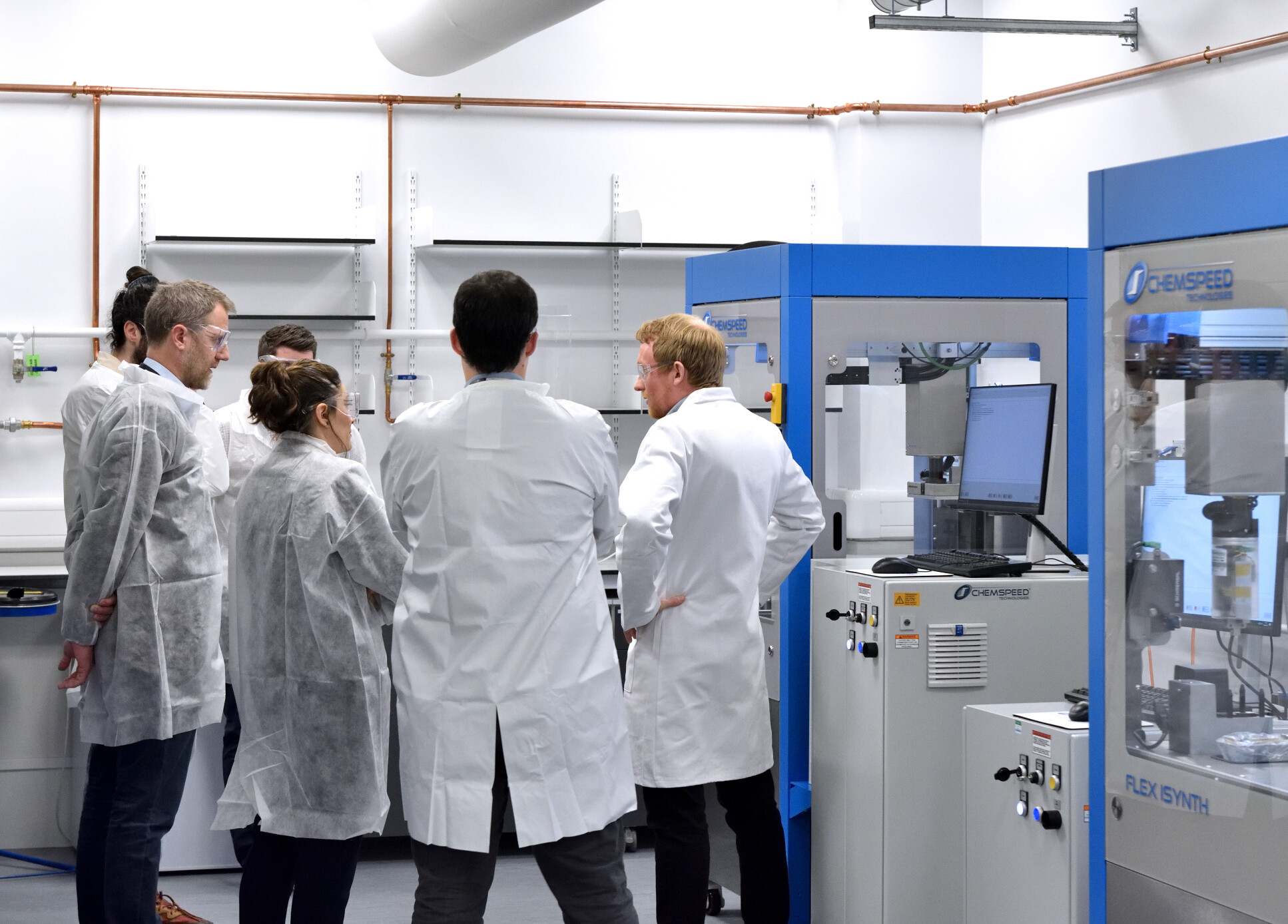 A group of men and women in labs coats in a lab setting