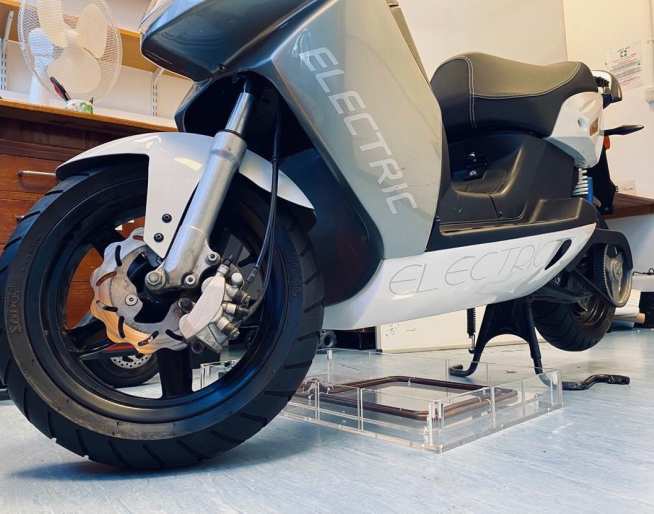 An electric scooter re-charging its batteries using one of Bumblebee Power's wireless charging pads