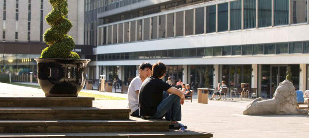 Two students sit on steps by the Queen's Tower