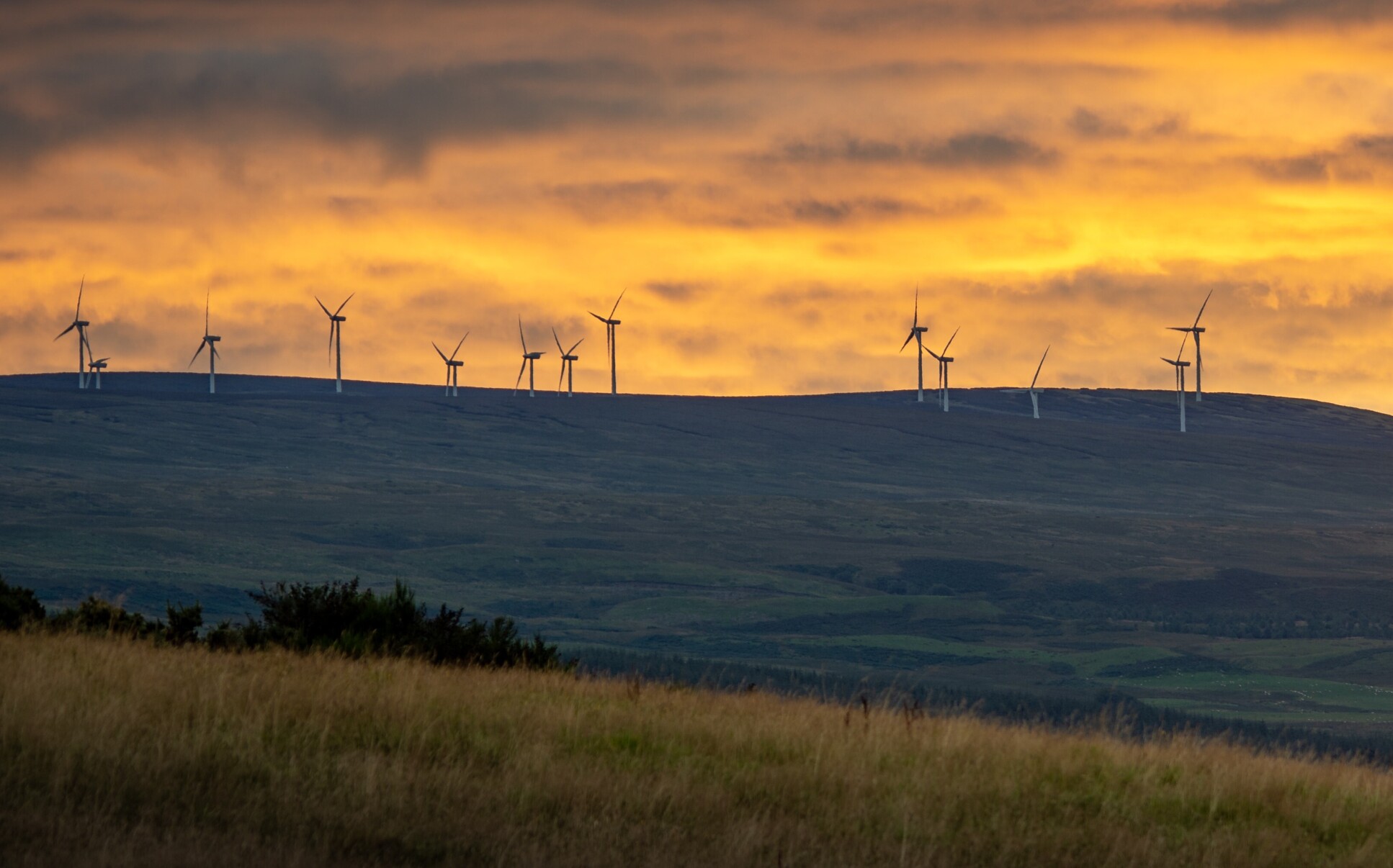 Wind turbines on a hill at sunset in Scottland.