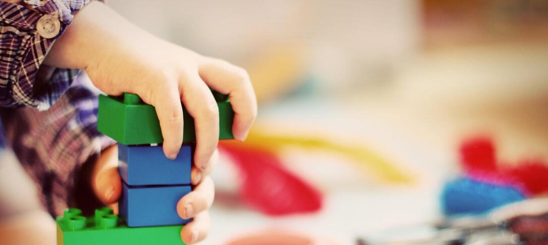 child's hand playing with primary colour plastic bricks