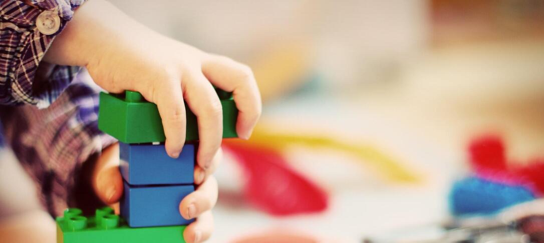 child's hand playing with primary colour plastic bricks