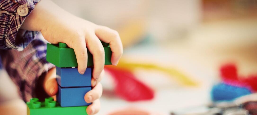 child's hand playing with primary colour plastic bricks