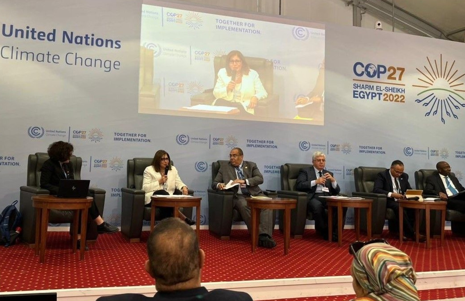 Photo of six people sitting on a stage speaking to an audience, the backdrop says United Nations Climate Change, COP27 Sharm El-Sheikh Egypt 2022