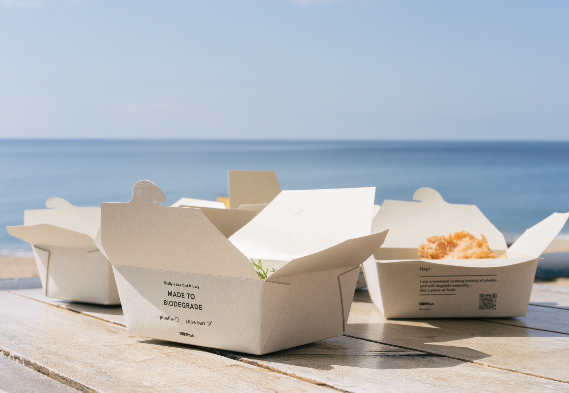 Takeaway containers on a table with the sea in the background