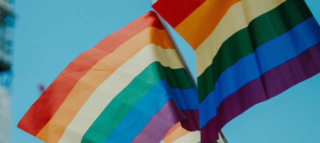 Two rainbow flags flying in the sky