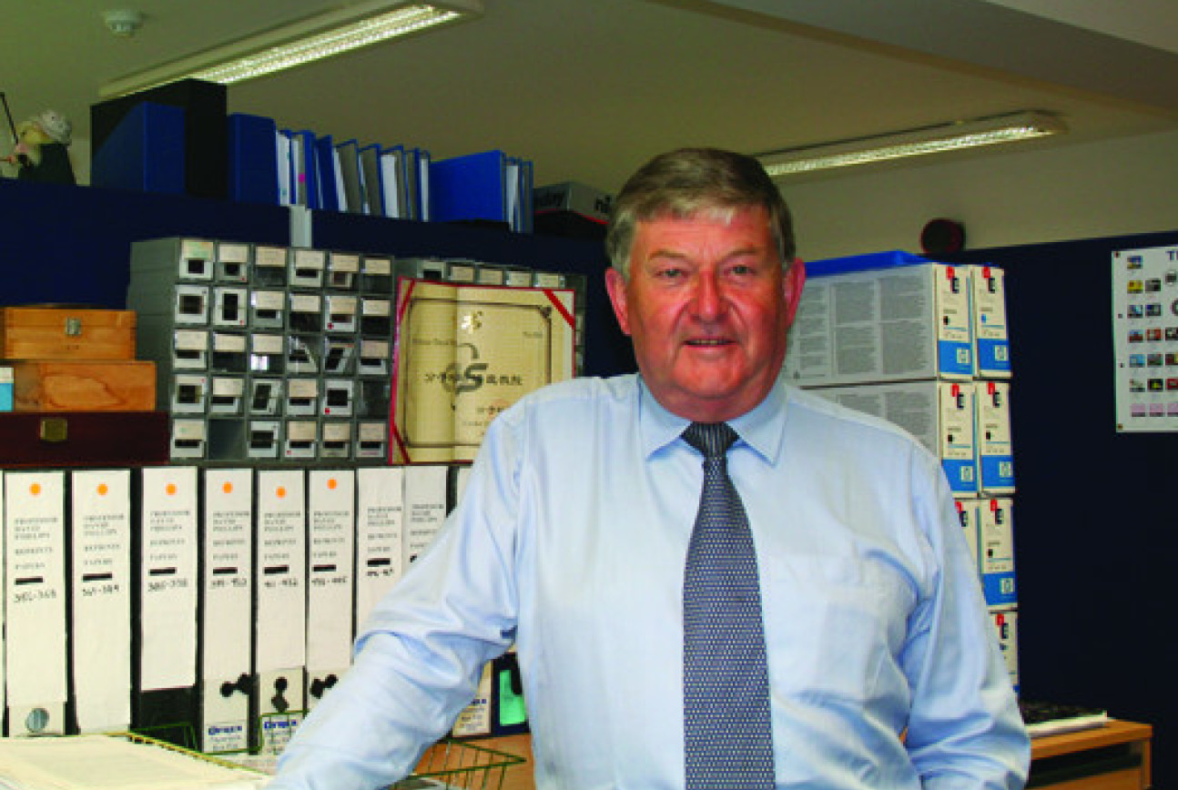 Man in shirt and tie standing in office with files