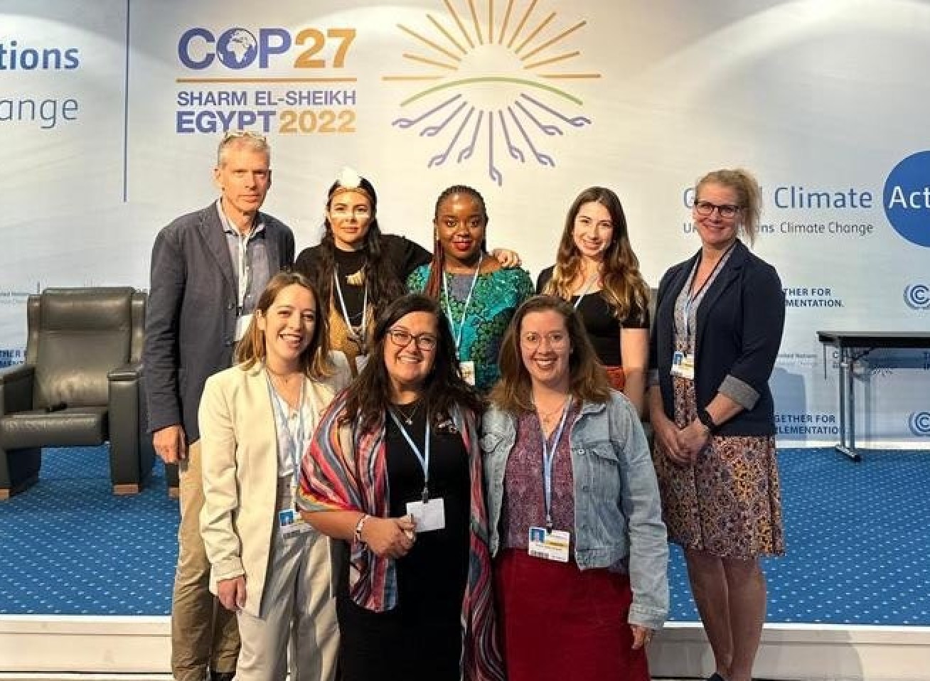 Dr Lawrance poses with a group of colleagues in front of a COP27 sign
