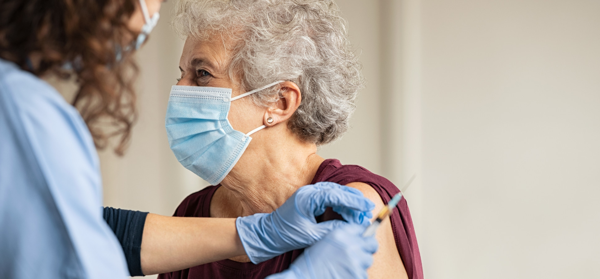 Image of a woman receiving a vaccine from a medical professional.
