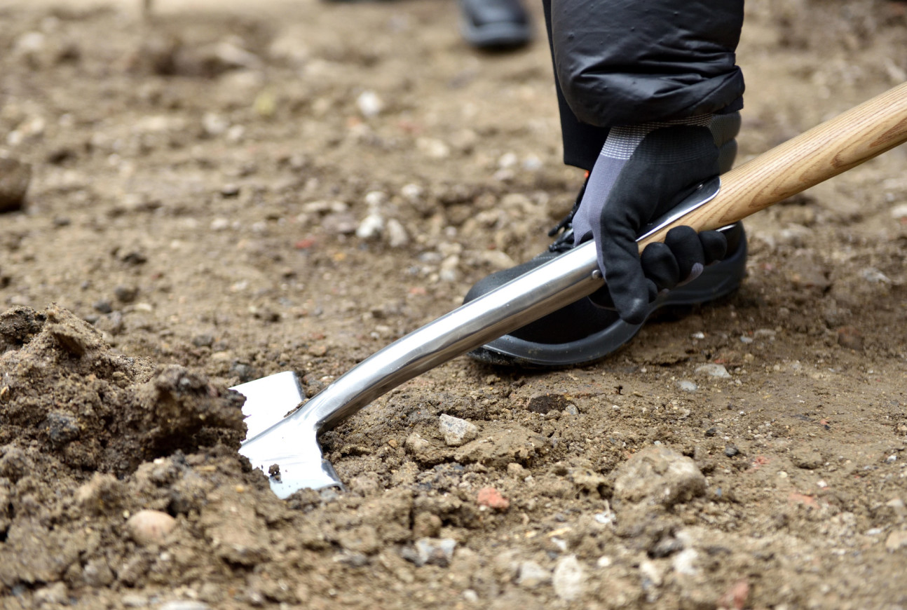 Person holding a spade in the ground