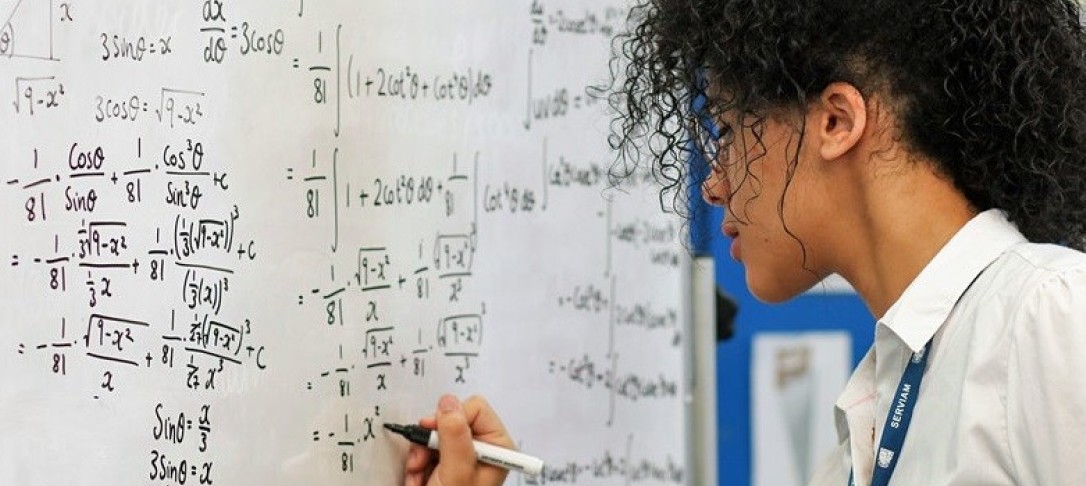 A black student working out a mathematical equation at a whiteboard