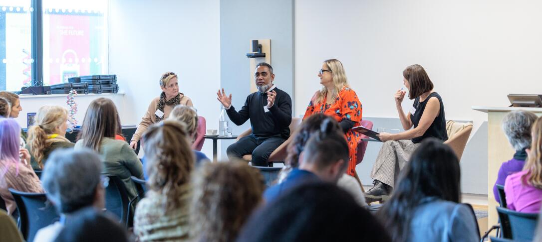 Panel discussion featuring three panel members and chair, picture from the back of the room behind seated audience members