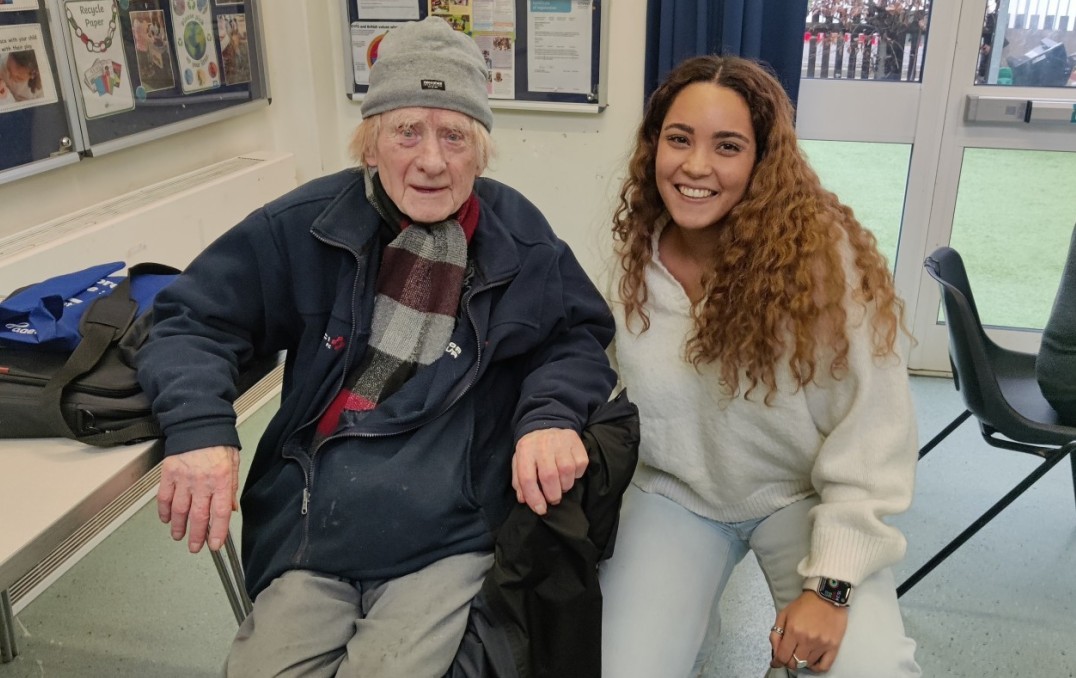 A 'What The Tech?!' volunteer taking a picture with participants in the community programme 