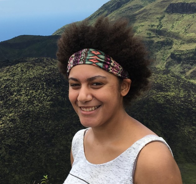 Jazmin Scarlett, a mixed race woman with black curly hair in a bandana stands in front of a volcano