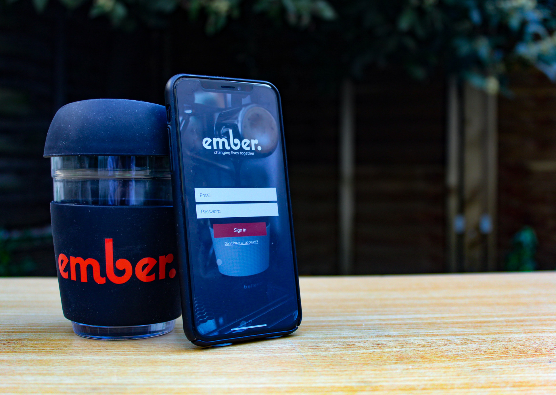 A mobile phone leaning against a coffee cup