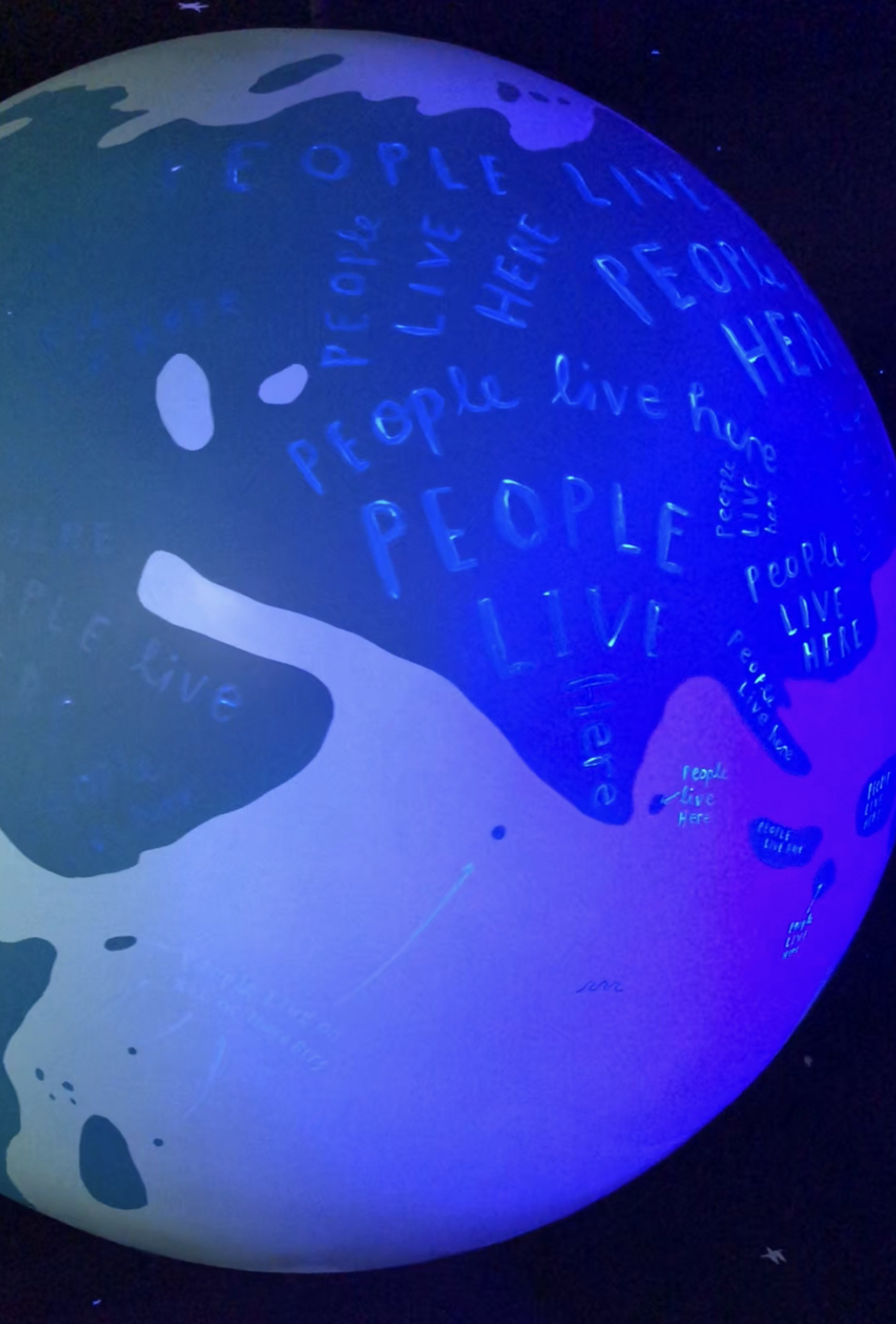 Photo of glow in the dark globe with 'people live here' written on it in glow in the dark paint