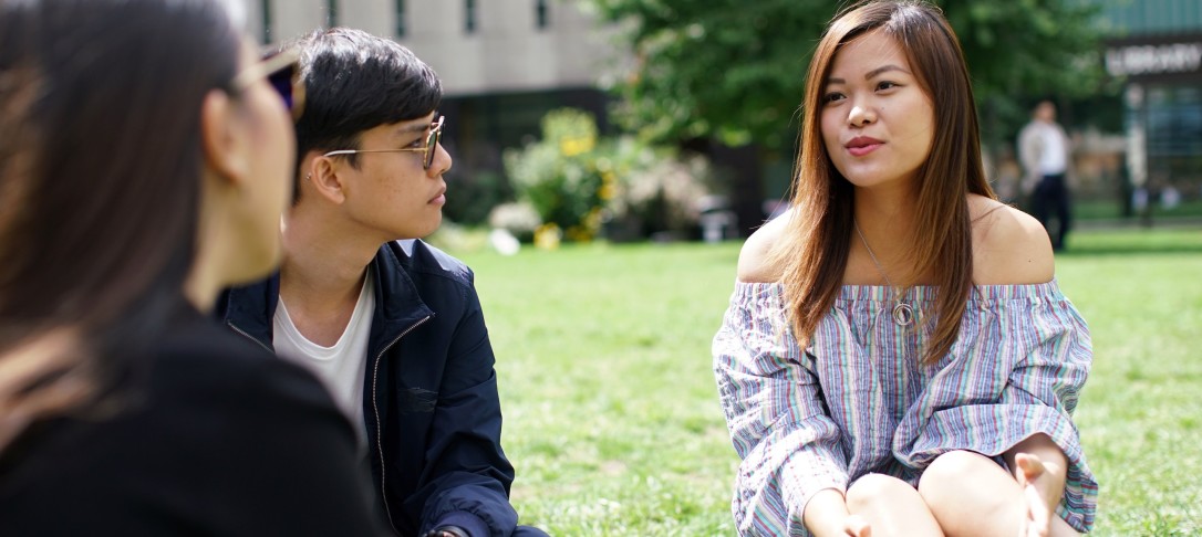Image of three students sitting on grass