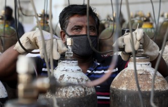 An Indian health worker with oxygen tanks