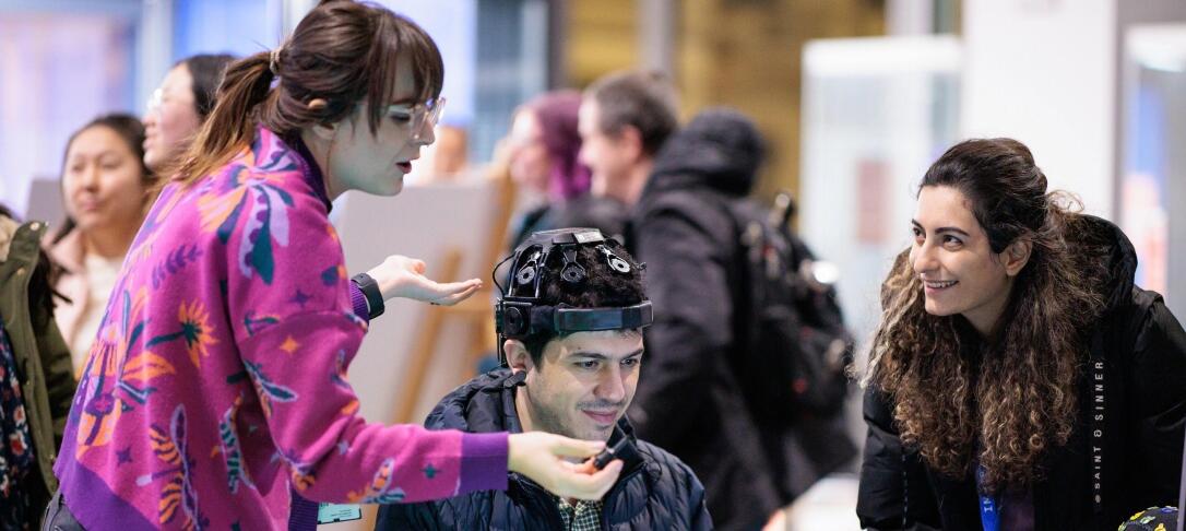 A researcher explaining a piece of wearable tech to two Imperial Lates visitors