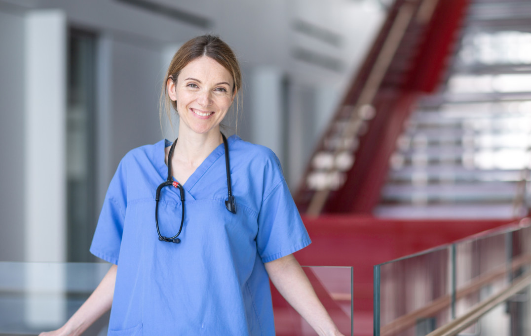 Katrina Pollock smiles at the camera, wearing scrubs and a stethoscope around her neck