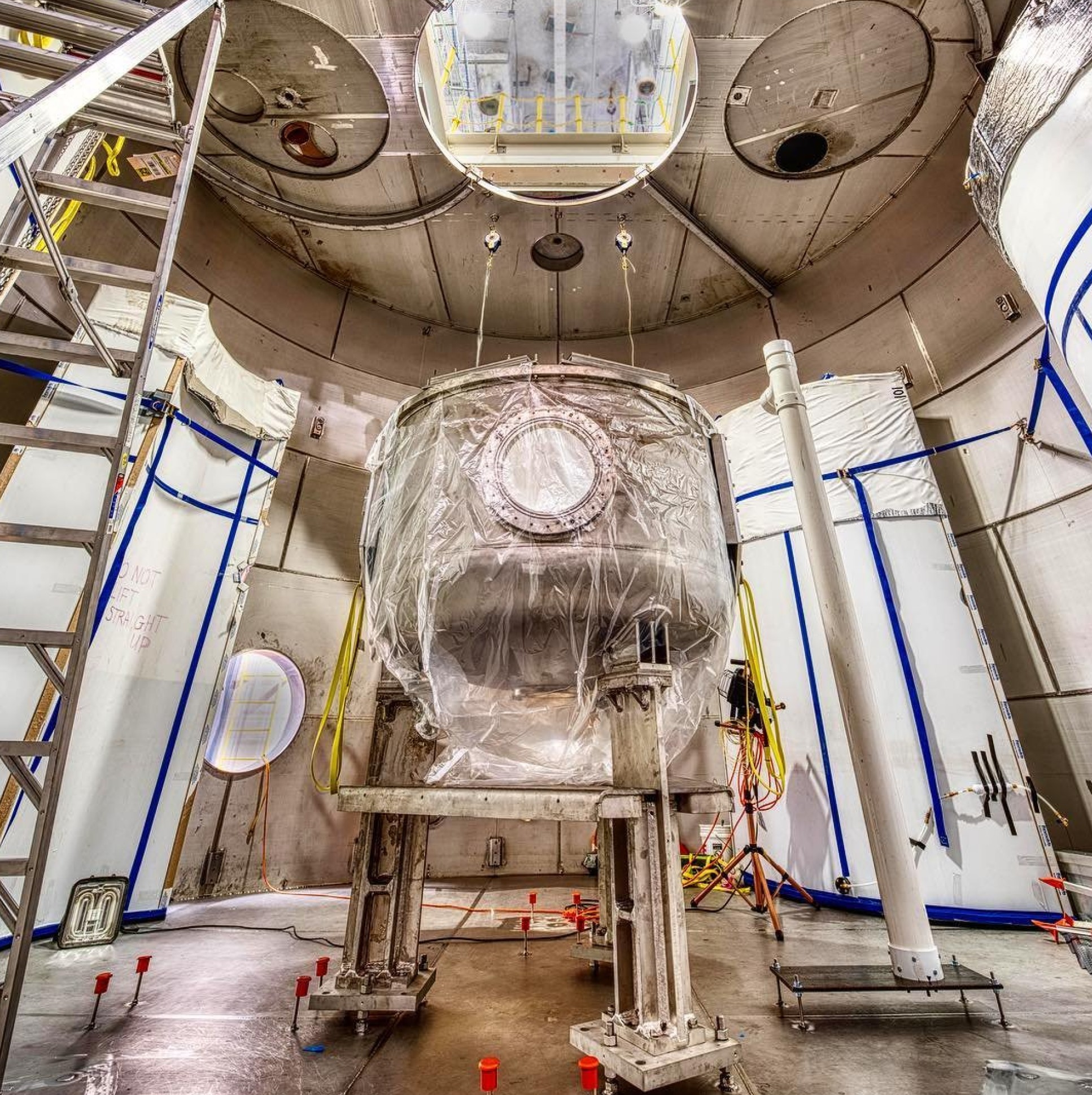 A large round vessel on scaffolding within a large concrete chamber