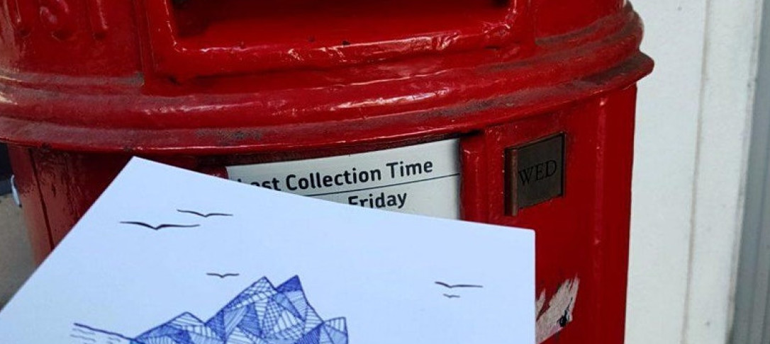 Hand-drawn postcard being put into red post box