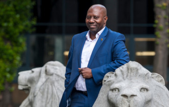 Dr Sunday Popo-Ola next to a stone lion at the Queen's Tower