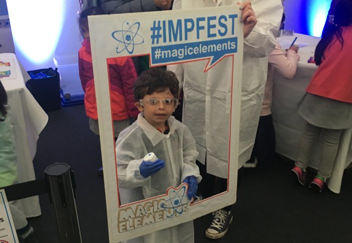 Young boy dressed as scientist in white coat, gloves and goggles