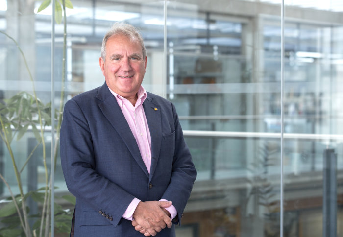 man in navy jacket in front of glass background