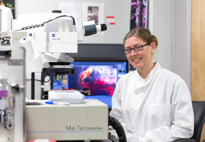 Dr Lo Celso in front of a large microscope