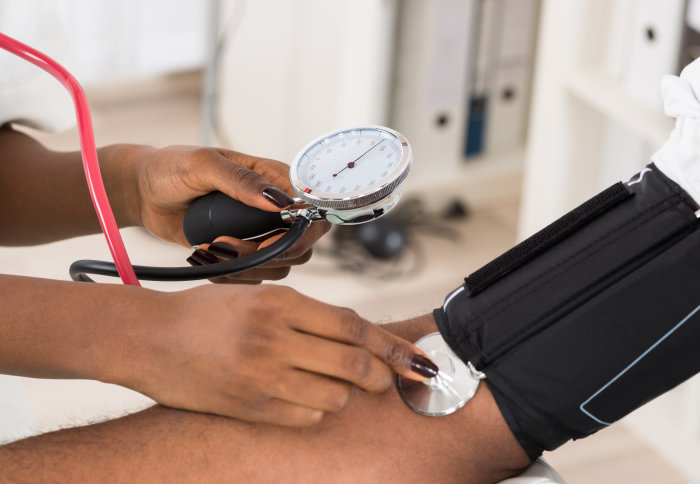 A health worker takes a blood pressure reading from a man's arm