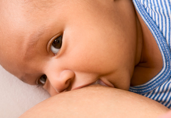 Closeup of newborn baby breastfeeding from its mother