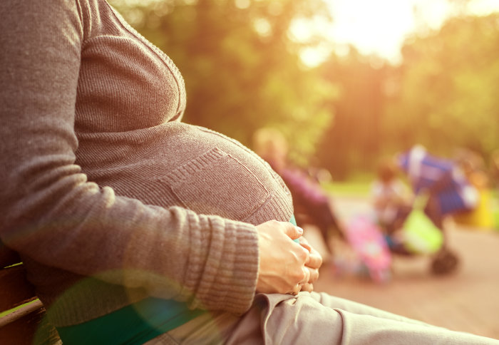 Pregnant woman sits on a bench