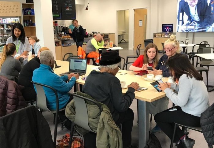Senior citizens with their gadgets and some students in a cafe