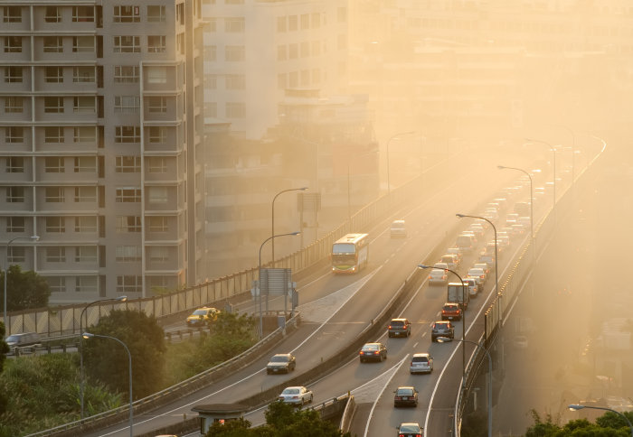 Air pollution scenic with cars on highway and yellow smoke in city.