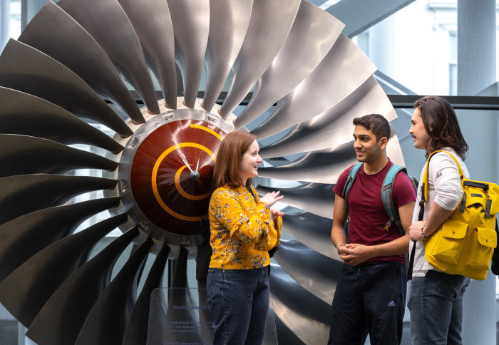 Students talking by turbine in the Royal School of Mines building