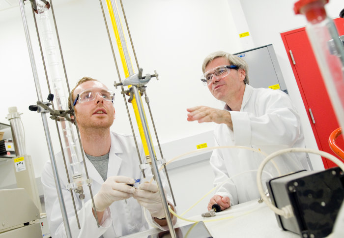 Two men in a lab looking at some tubes