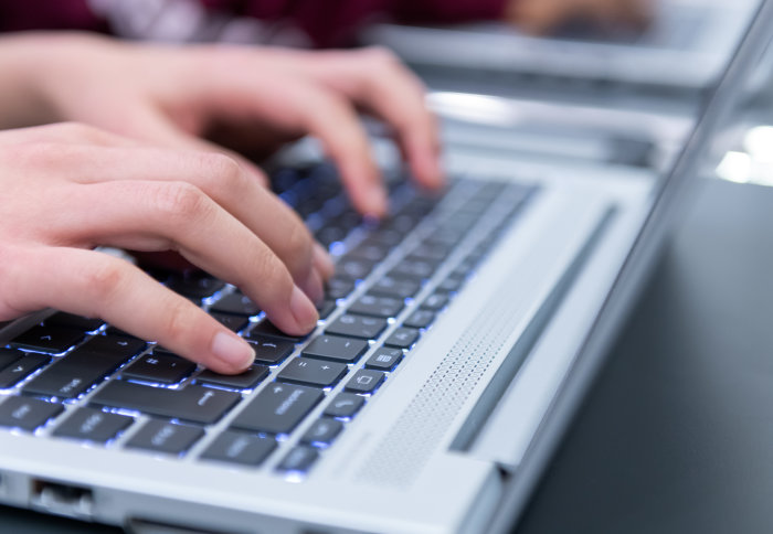 Student types on laptop keyboard