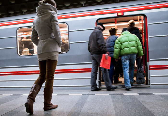 Photo of lone woman walking towards a crowded metro