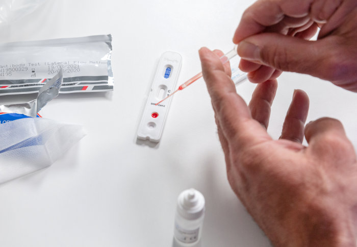 A person putting a drop of blood onto the coronavirus home testing cassette for COVID19