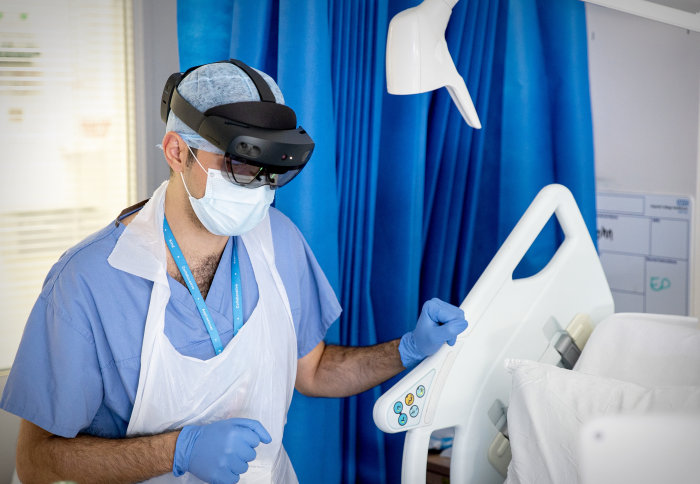 A photograph of a doctor wearing the HoloLens leadset alongisde PPE