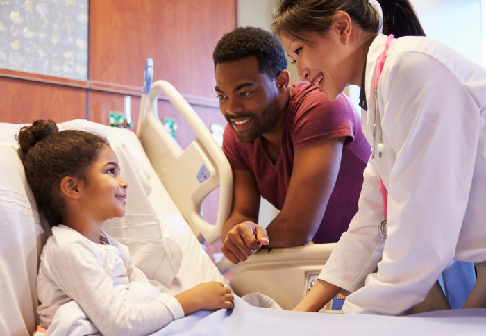 Child in a hospital bed with her father and a doctor