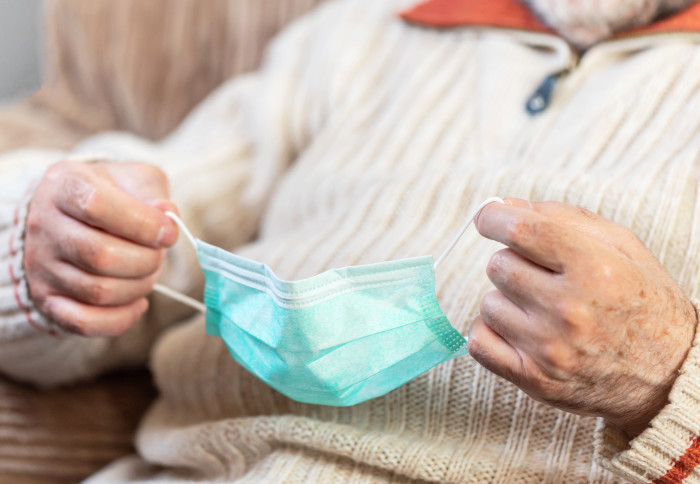 Close-up view of an elderly person putting on mask to protect against coronavirus infection