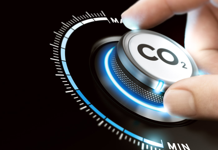 Man turning a carbon dioxide knob to reduce emissions. CO2 reduction or removal concept. Composite image between a hand photography and a 3D background.