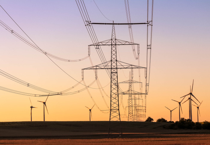 Electricity pylons with wind turbines in the background