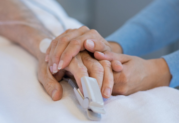 An elderly hand holding a younger hand