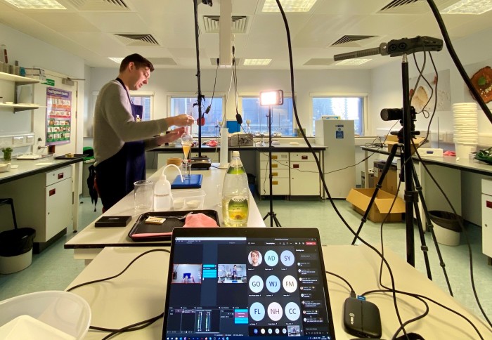 man in lab with cameras and microphone set up, with laptop showing Teams in the foreground