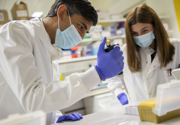 The Chancellor uses a pipette in lab